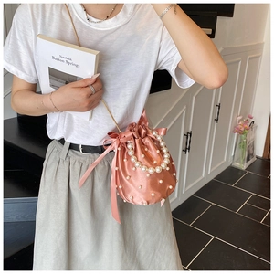 Detailed shot of pink satin bucket bag with pearl embellishments and golden chain strap