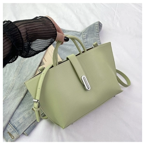 Detail of light green pebbled leather bag with silver metal lock and adjustable strap