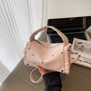 Pink Boston handbag with silver heart studs and adjustable strap on a minimalist desk