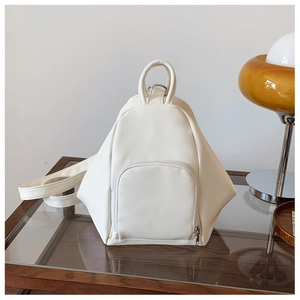 Detail of white triangle backpack showing pebbled faux leather texture and sturdy top handle