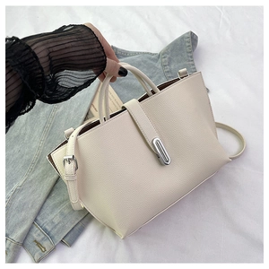 Detail of cream pebbled leather tote bag with silver metal clasp on casual background