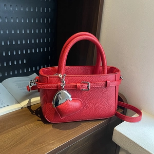 Red litchi grain handbag with heart pendant and adjustable strap for shoulder or crossbody