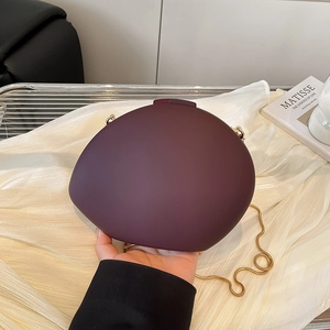 Oval acrylic shell clutch bag in deep burgundy with a gold snake chain strap
