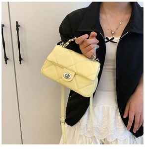 Detail of yellow quilted crossbody bag featuring silver oval twist lock and chain handle
