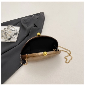 Detail of acrylic marble evening bag with gold spherical clutch with golden chain strap and interior lining