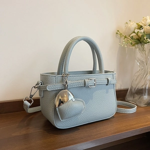 Light blue lychee pattern handbag with heart pendant and silver buckle on a wooden shelf