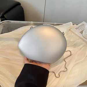 Matte silver oval clutch bag with metal chain strap held against silk background