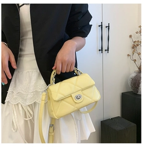 Detail of quilted light yellow handbag with silver twist lock and metal chain handle