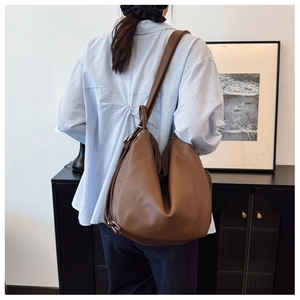 Brown leather hobo bag worn by model, showing spacious design and adjustable strap