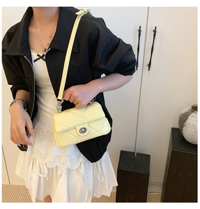 Pale yellow quilted crossbody bag with silver twist lock shown on model with lace dress