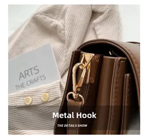 Detail of dark brown leather handbag featuring a high-gloss gold metal swivel hook