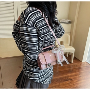Detailed view of pink rhinestone crossbody bag featuring lace bow and pearl pendant charm