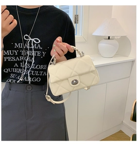 Detail of cream quilted handbag with classic diamond stitching and gold twist lock closure