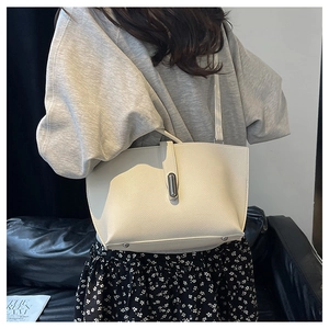 Chic beige pebbled leather tote bag with silver clasp detail shown on a model