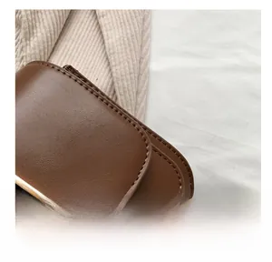 Detailed close-up of precise stitching and gold metal buckle on a brown leather bag