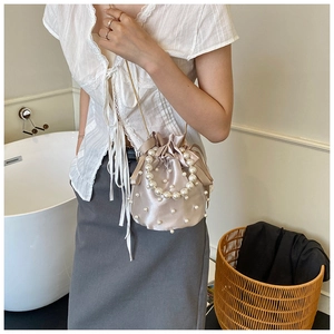 Elegant champagne satin drawstring bucket bag with pearl embellishments and chain strap