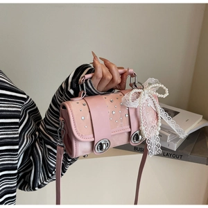 Detailed view of pink leather bag featuring rhinestone embellishment and lace bow charm