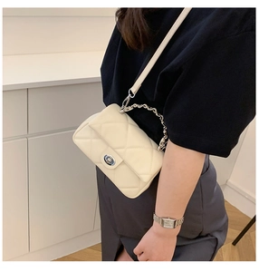 Detailed close-up of quilted off-white crossbody bag with silver twist lock and chain strap