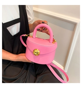 Detail of pink leather handbag with round handle and gold-tone embossed metal buckle