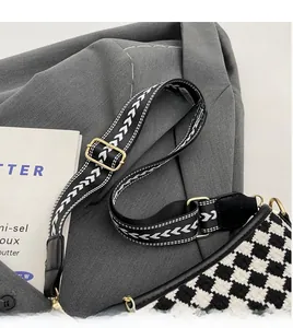 Detail of houndstooth bucket bag with wide arrow pattern strap and gold hardware