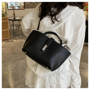 Detail of black pebbled leather tote bag with silver metal twist lock and single handle