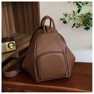Detail of vintage brown textured leather backpack with a half-moon zipper pocket on a desk