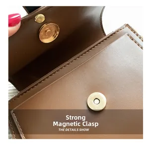Close-up of golden magnetic closure and brown lychee grain leather texture on a handbag