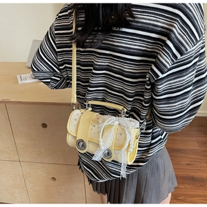 Detail of light yellow crossbody bag featuring lace bow, pearls, and rhinestone accents