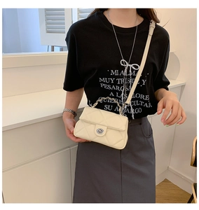 Detail of off-white quilted crossbody bag featuring silver metal twist lock and chain handle