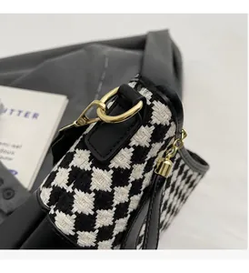 Close-up of houndstooth fabric bucket bag with gold hardware and black leather trim