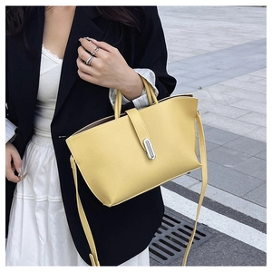 Detailed shot of yellow litchi leather tote bag with silver metal twist lock and handles