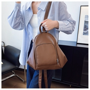 Close-up of brown PU leather backpack featuring fine lychee texture and silver zipper detail