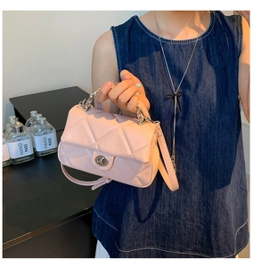 Detail of pink quilted handbag featuring a silver twist lock and metal chain handle