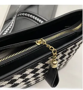 Close-up of smooth gold zipper and black houndstooth pattern on the bucket bag