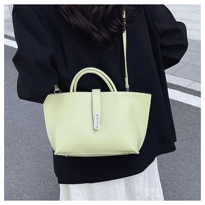 Close-up of pistachio green pebble leather handbag with silver oval metal buckle