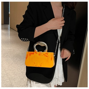 Détail du sac boîte en acrylique marbré orange avec poignée et chaîne argentées