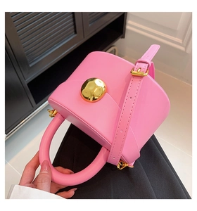 Close-up of rose pink leather bag featuring a large decorative gold spherical metal lock