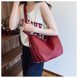Detail of burgundy pebbled leather crescent bag with adjustable strap worn by model