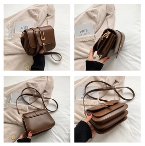 Detail view of brown vintage satchel with three compartments and gold hardware buckle