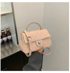 Detailed view of pale pink quilted crossbody bag featuring silver metal twist lock clasp