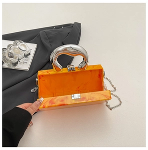 Vue détaillée de la pochette de soirée en acrylique orange marbré avec anse argentée