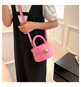 Close-up of pink minimalist handbag with gold snap button and matching leather strap