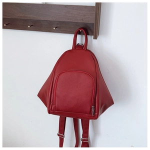Detail view of red faux leather backpack featuring pebbled texture and metal hardware