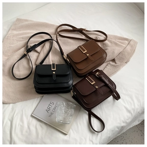 Three minimalist flap square bags in black and brown leather with gold buckles on fabric