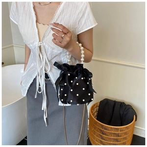 Detail of black satin bucket bag featuring pearl handles and elegant drawstring closure