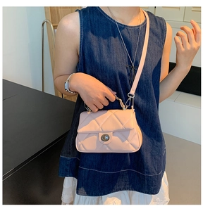 Detail of light pink quilted handbag featuring metal twist lock and chain handle