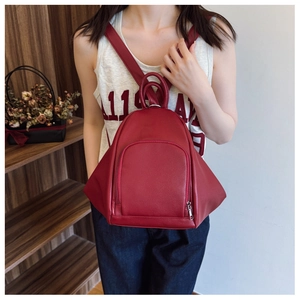 Detail of red faux leather backpack with pebble texture and metallic top handles