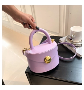 Detail of lavender leather handbag with bold gold circular lock and textured surface