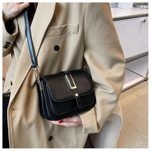 Detail of black vintage leather crossbody bag featuring a vertical gold metal buckle