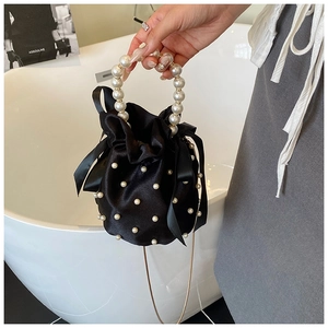 Detail of black satin bucket bag with pearl embellishments and knotted silk bows